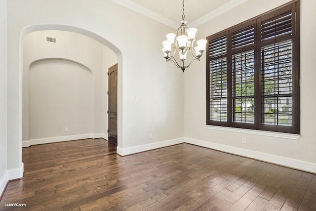 empty room with crown molding, dark hardwood / wood-style flooring, and a chandelier