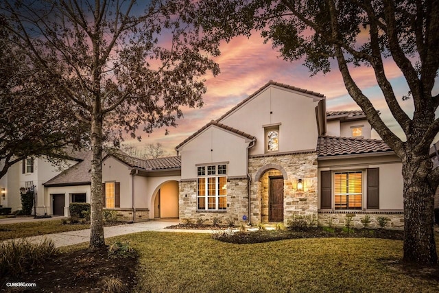 mediterranean / spanish house featuring a garage and a yard