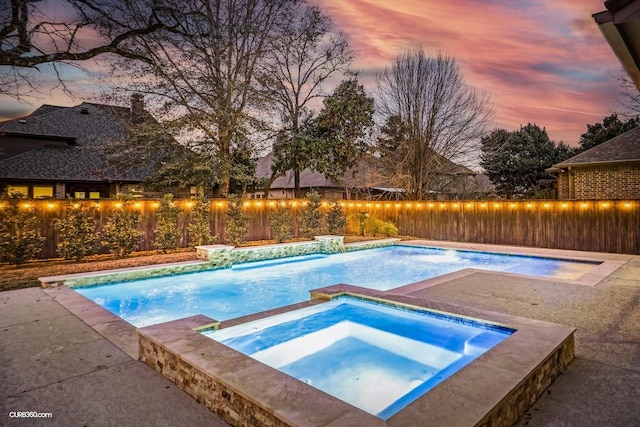 pool at dusk with an in ground hot tub and pool water feature