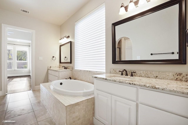 bathroom with tile patterned flooring, vanity, and tiled tub