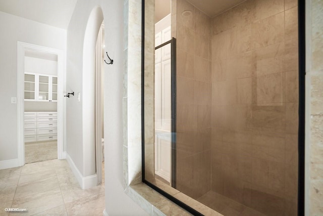 bathroom with tiled shower and tile patterned flooring