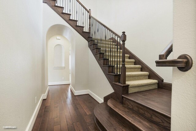 stairway featuring hardwood / wood-style flooring and a towering ceiling