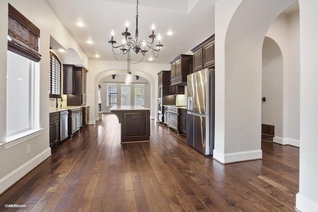 kitchen with decorative light fixtures, dark wood-type flooring, a center island, and appliances with stainless steel finishes