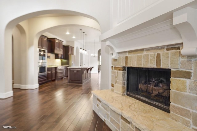 living room with dark hardwood / wood-style flooring and a stone fireplace