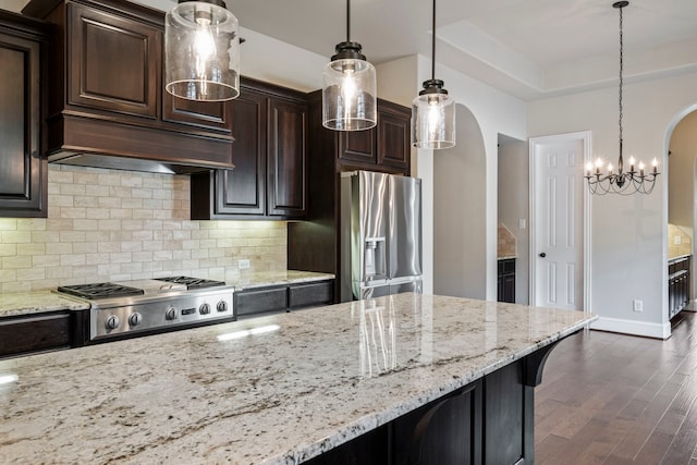 139 Monterrey Bnd, Montgomery, TX 77316 - kitchen featuring tasteful backsplash, arched walkways, light stone countertops, appliances with stainless steel finishes, and dark wood-type flooring