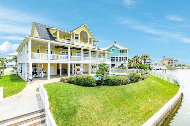 back of house with a patio, a balcony, a lawn, a fenced in pool, and a water view