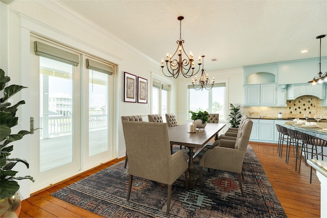 dining space with wood-type flooring, crown molding, and a chandelier