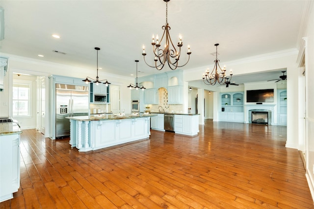 kitchen with a center island, ornamental molding, pendant lighting, stainless steel appliances, and white cabinets