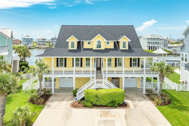 view of front of property featuring a garage, a front lawn, a porch, and a water view