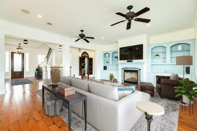 living room with ceiling fan, ornamental molding, a fireplace, and hardwood / wood-style floors