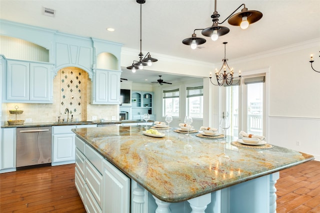 kitchen with crown molding, stainless steel dishwasher, a center island, and sink