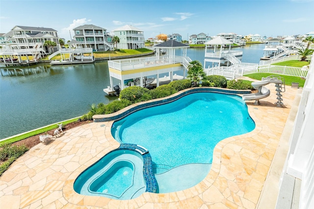 view of swimming pool with a water slide, a patio, and a water view