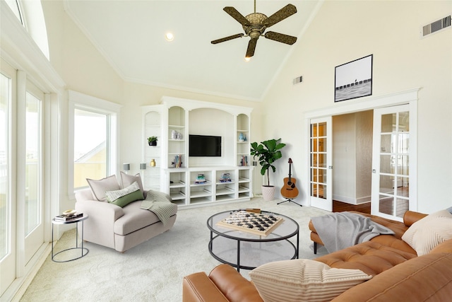 carpeted living room with ceiling fan, high vaulted ceiling, and french doors