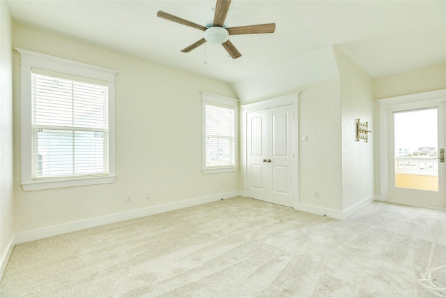 unfurnished bedroom featuring lofted ceiling, light carpet, multiple windows, and ceiling fan