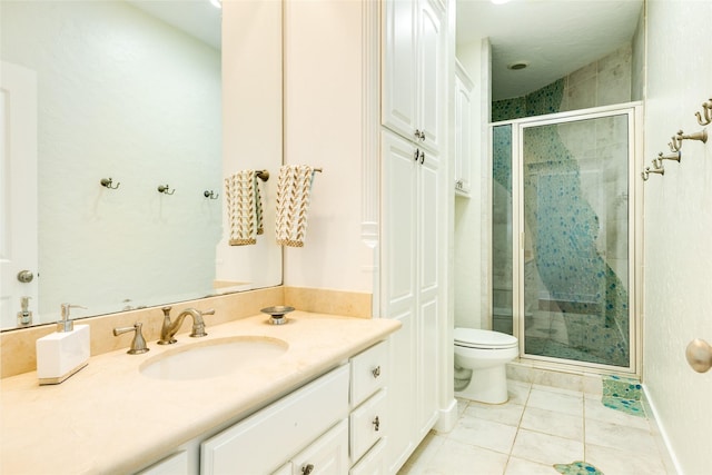 bathroom with tile patterned floors, vanity, toilet, and a shower with door