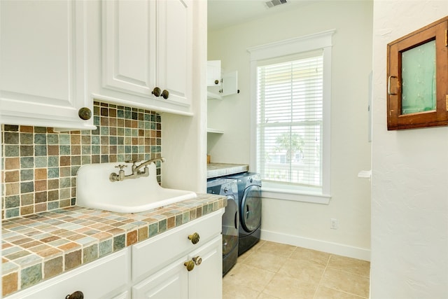 clothes washing area featuring cabinets, sink, light tile patterned floors, and washing machine and clothes dryer