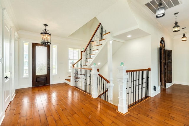 entrance foyer with crown molding, hardwood / wood-style flooring, and a chandelier