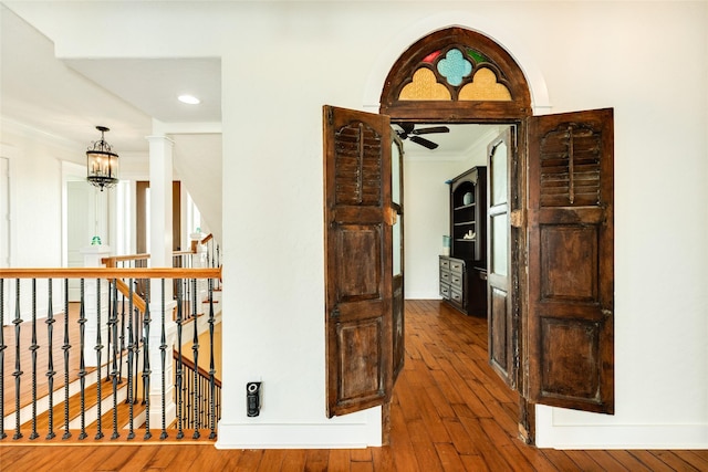 corridor featuring an inviting chandelier, ornamental molding, dark hardwood / wood-style flooring, and decorative columns