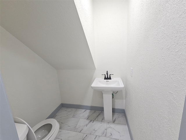 bathroom featuring vaulted ceiling and toilet