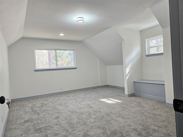 bonus room featuring lofted ceiling, a healthy amount of sunlight, and light carpet