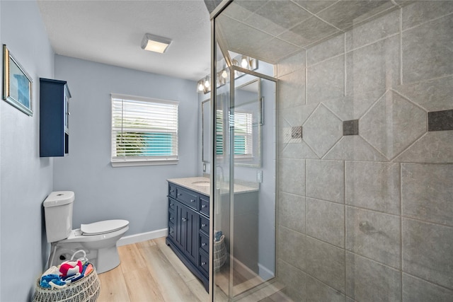 bathroom featuring vanity, wood-type flooring, a shower with shower door, and toilet