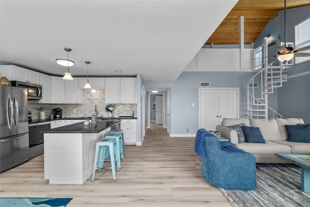 kitchen with white cabinetry, a kitchen island, a breakfast bar, and appliances with stainless steel finishes