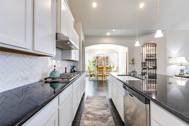 kitchen with dark stone counters, stainless steel appliances, under cabinet range hood, white cabinetry, and a sink