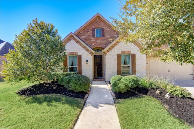 view of front of house with a garage, concrete driveway, stone siding, a front yard, and brick siding