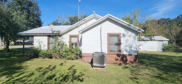 rear view of property featuring cooling unit and a lawn