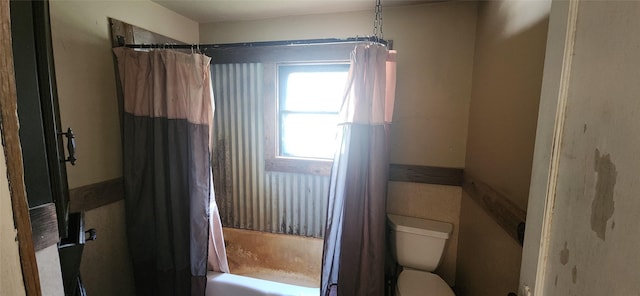 bathroom with shower / bathtub combination with curtain and toilet