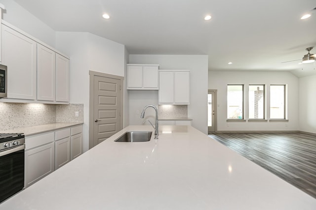 kitchen with sink, tasteful backsplash, wood-type flooring, stainless steel range, and white cabinets