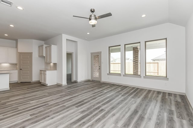 unfurnished living room with ceiling fan, vaulted ceiling, and light hardwood / wood-style flooring