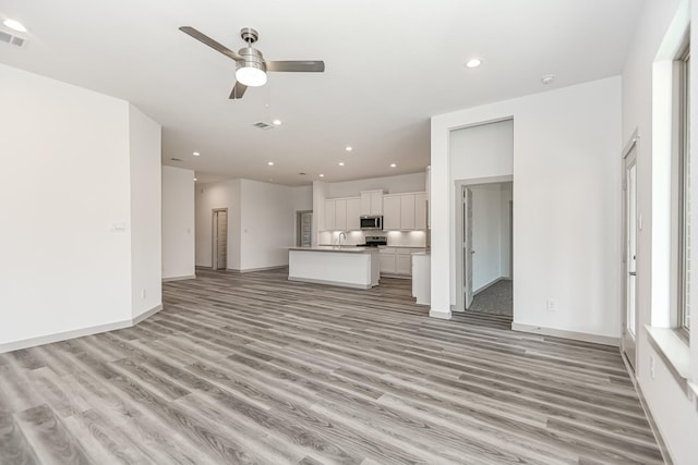 unfurnished living room featuring sink, light hardwood / wood-style flooring, and ceiling fan