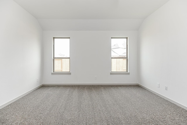 carpeted empty room with vaulted ceiling