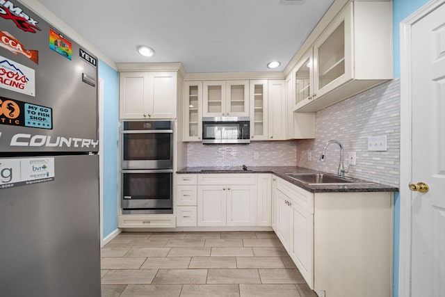 kitchen with appliances with stainless steel finishes, tasteful backsplash, white cabinetry, sink, and dark stone counters