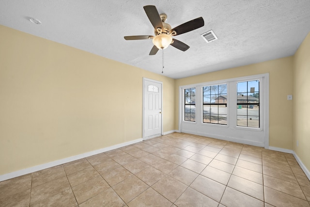 tiled empty room with ceiling fan and a textured ceiling