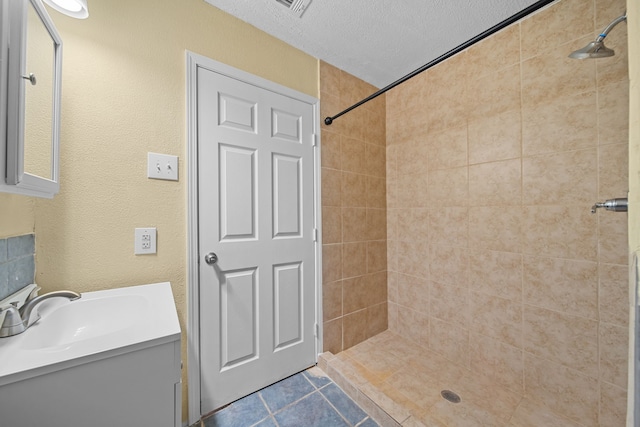 bathroom with vanity, a textured ceiling, and tiled shower