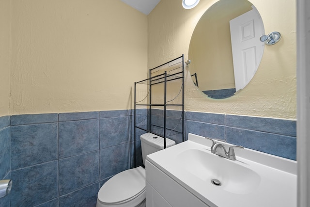 bathroom featuring vanity, toilet, and tile walls