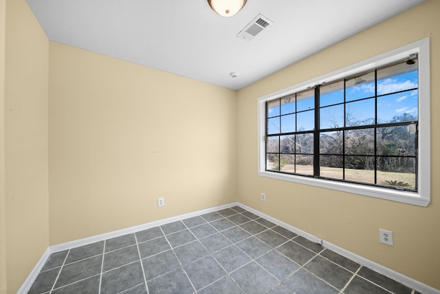 spare room featuring dark tile patterned floors