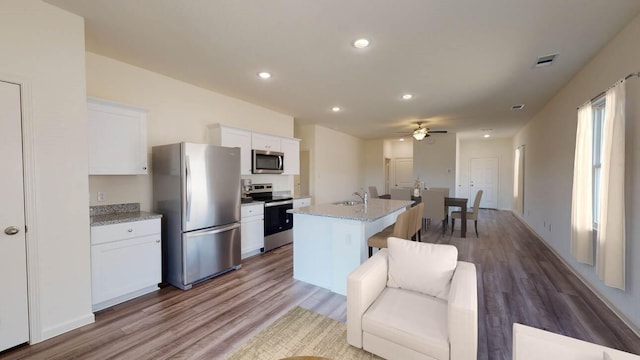 kitchen featuring sink, white cabinetry, appliances with stainless steel finishes, light stone countertops, and a kitchen island with sink