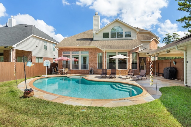 rear view of house featuring brick siding, a fenced backyard, a chimney, and a patio