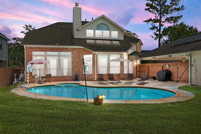 pool at dusk featuring a jacuzzi, a fenced backyard, and a patio area