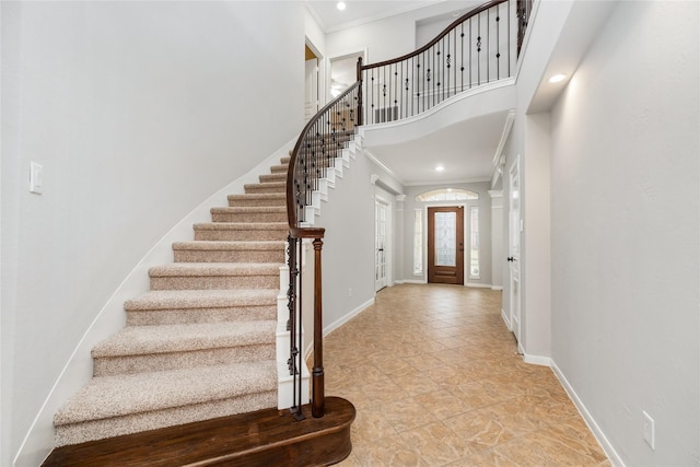 foyer entrance with recessed lighting, a high ceiling, baseboards, and ornamental molding