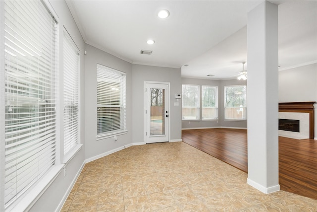 interior space with crown molding, a fireplace, visible vents, and baseboards