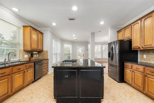 kitchen featuring a sink, a kitchen island, appliances with stainless steel finishes, and dark stone countertops