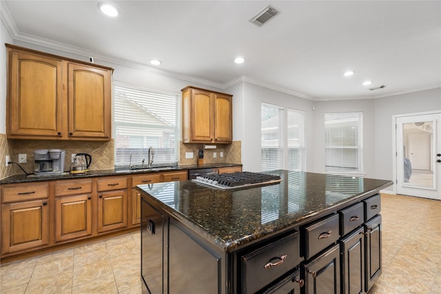 kitchen featuring visible vents, a sink, tasteful backsplash, dark stone counters, and crown molding