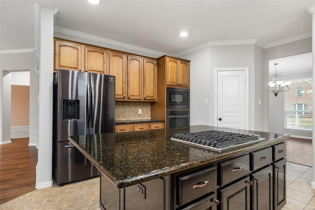 kitchen with tasteful backsplash, crown molding, dark stone countertops, a notable chandelier, and black appliances