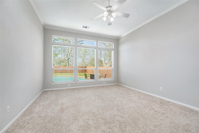 carpeted spare room featuring visible vents, a ceiling fan, baseboards, and ornamental molding