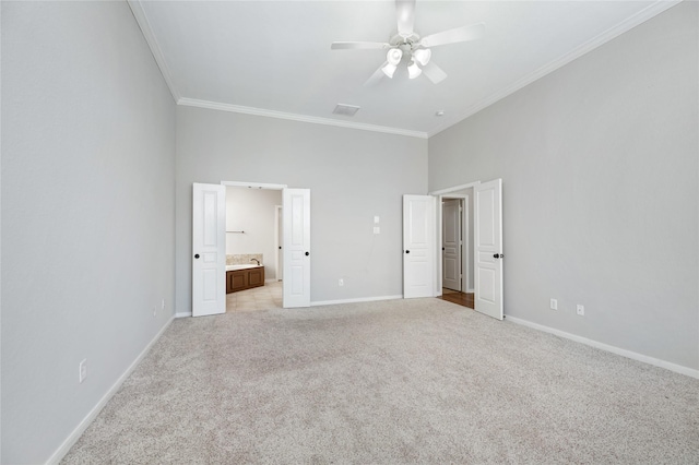 unfurnished bedroom with visible vents, ensuite bath, crown molding, baseboards, and light colored carpet