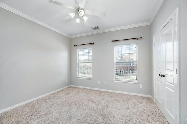 carpeted empty room featuring visible vents, baseboards, a ceiling fan, and crown molding